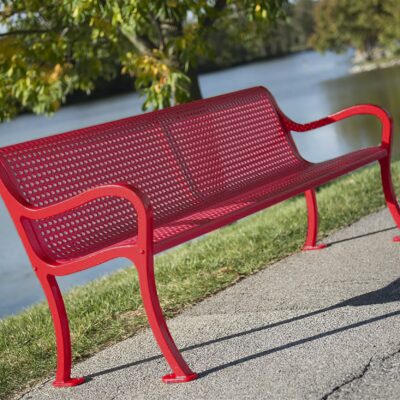 Red metal bench by a body of water with greenery