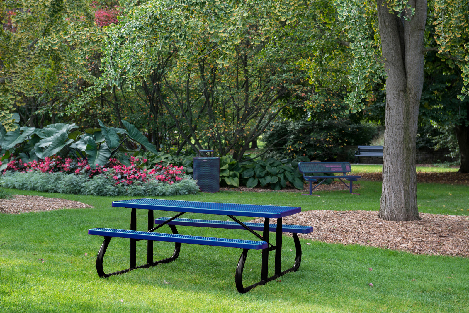 Wabash Valley blue picnic table in a park setting with trees and flowers