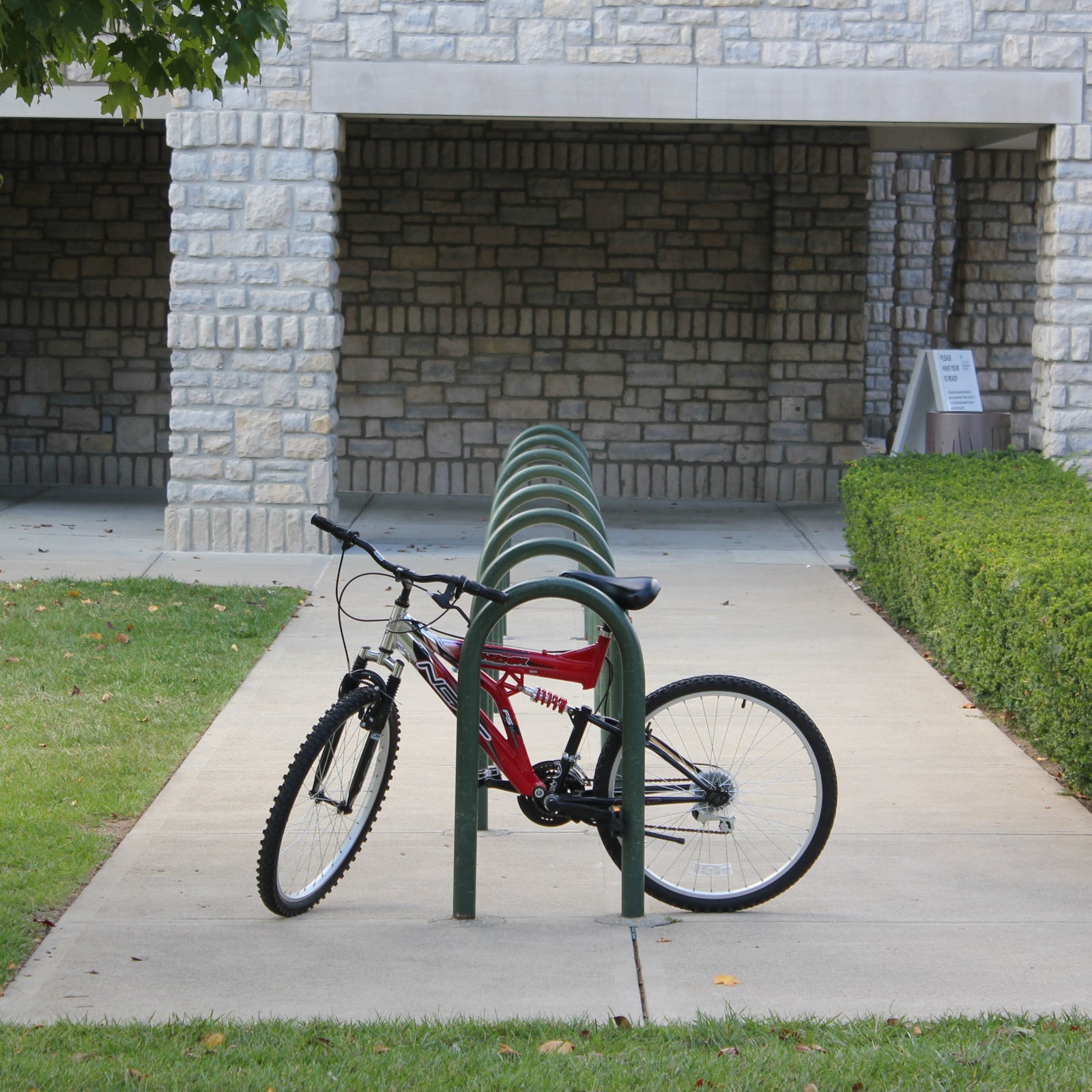 Red bicycle on a bike rack in front of a stone building